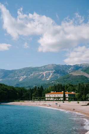Waves roll on the sandy beach near Villa Milocer at the foot of the mountains. Montenegro