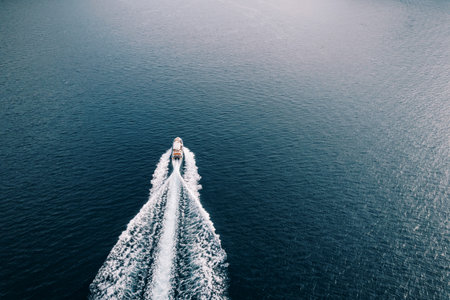 Speedboat sails across the sea leaving a white foamy trail. Back view. Droneの写真素材