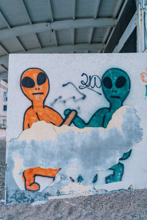 Scraped graffiti on a concrete wall depicting aliens shaking handsの写真素材