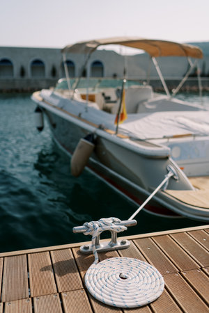 Motor yacht is moored to the pier with a striped rope wrapped around a bollard. Back viewの写真素材
