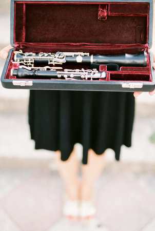 Young woman with a clarinet in an open case stands on the steps of a building. Cropped. Facelessの写真素材