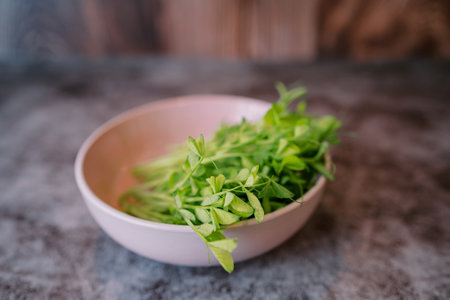 Bunch of fresh pea microgreens lies in a pink plate on a marble tableの写真素材