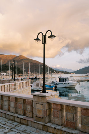 Stone fence with moored yachts against the backdrop of mountains at sunsetの写真素材