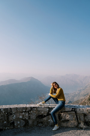 Woman in sunglasses sits with her head resting on her hand on a fence over the Bay of Kotor. Montenegroの写真素材