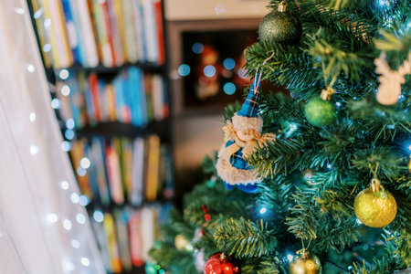 Figurine of a girl in a fur coat and hat hangs among gold and green balls on a Christmas treeの写真素材