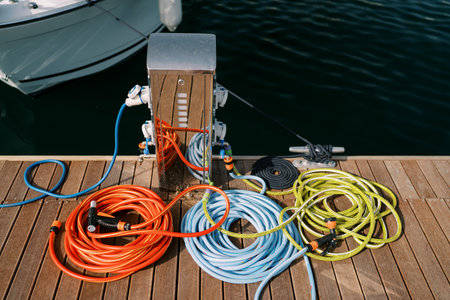 Colorful hoses with sprinklers connected to taps at an electric charging station on the pier