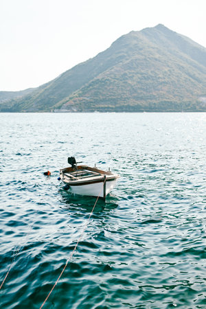 Fishing boat sways moored in the sea against the backdrop of mountainsの写真素材