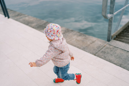 Small child runs along the promenade by the sea. Top viewの写真素材