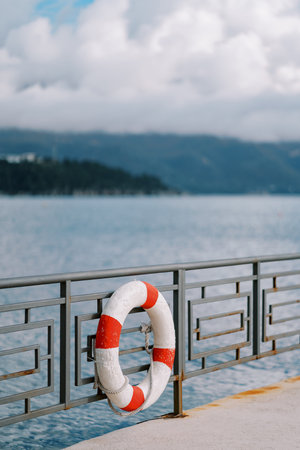 Striped lifebuoy hangs on a metal embankment fenceの写真素材