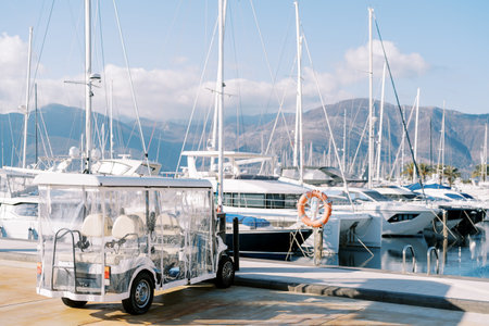 White golf cart parked on the boardwalk near moored yachts. High quality photoの写真素材