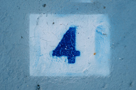 Number four with blurred edges drawn on a blue wall in a white rectangle. High quality photo