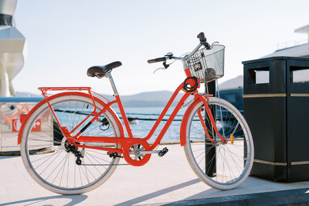 Rental red bicycle with basket attached to a pole on the boardwalk. High quality photoの写真素材