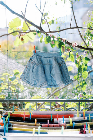 Small children denim jacket hangs on a rope above the clothes dryer on the balcony. High quality photoの写真素材