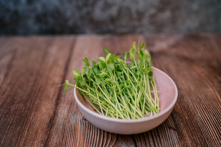 Microgreen pea sprouts in a bowl on a wooden tableの写真素材