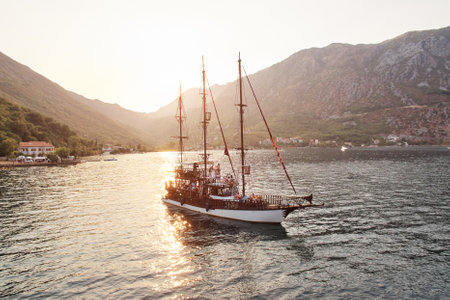 Sailboat sails on the sea with tourists on board along the mountainous coastの写真素材
