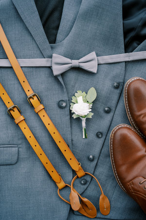 Leather suspenders, men shoes and a boutonniere lie on the groom suitの写真素材