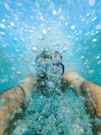 Swimmer in a mask swims in bubbles underwaterの写真素材