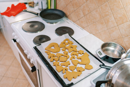 Baked ginger cookies of different shapes lie on a tray on the table near the ovenの写真素材