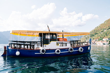 Colorful water bus moored in the harbor with mountains in the background