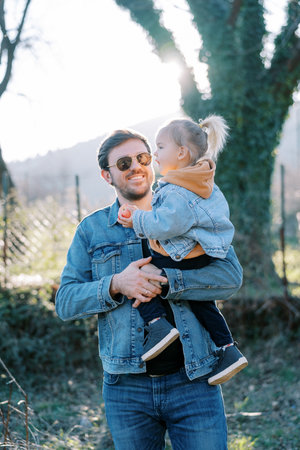 Smiling dad holding little girl with apple in his armsの写真素材