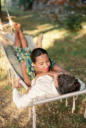 Smiling woman lying on man in a hammock, resting her hand on his chestの写真素材