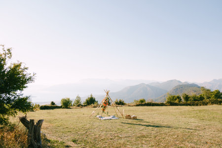 Wedding wigwam arch stands on a green meadow in the mountainsの写真素材