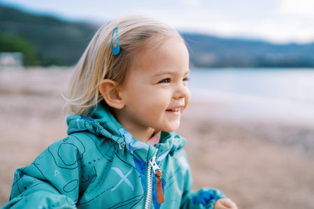 Little smiling girl stands on the beach and looks awayの写真素材
