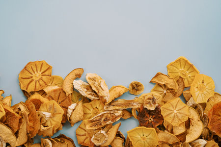 Pieces of dried fruits lie along the bottom edge on a blue backgroundの写真素材