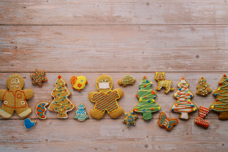 Colorful Christmas gingerbread cookies lie in a row on a light wooden backgroundの写真素材