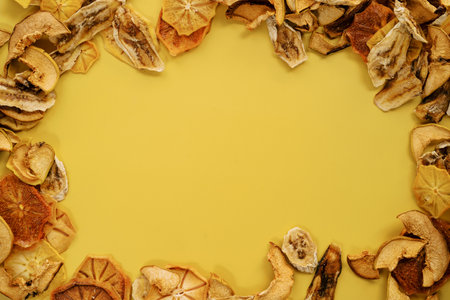 Oval ornament made of thin slices of dried fruits on a yellow backgroundの写真素材