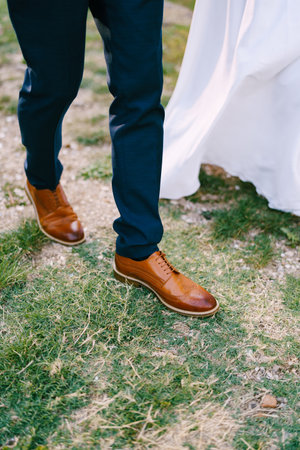 Groom in brown brogues walks next to the bride in a white dress. Cropped. Facelessの写真素材
