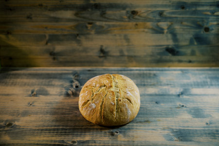 Round loaf of bread lies on a wooden tableの写真素材