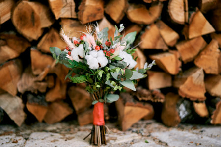 Wedding bouquet stands on a tile near a woodpileの写真素材