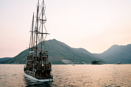 Sailboat sails along the Bay of Kotor against the backdrop of mountains and the island of St....