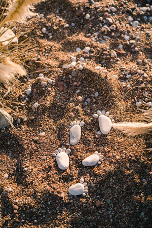 Footprints in the sand made of pebbles in sunlightの写真素材