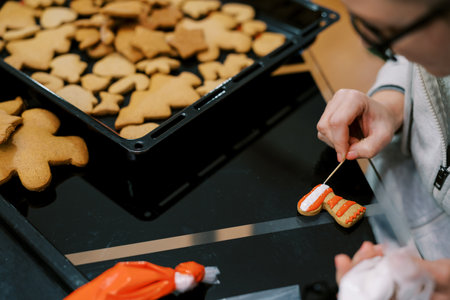 Confectioner uses a toothpick to apply a pattern of icing to a cookieの写真素材