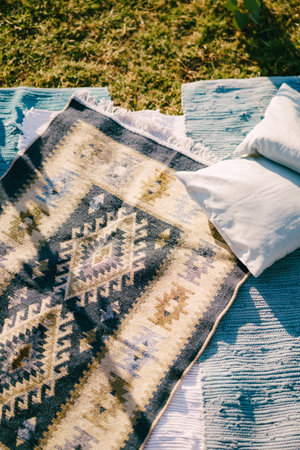 Pillows lie on homespun bedspreads on green grassの写真素材