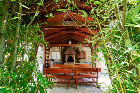 View through the green branches of the garden to a wooden gazebo with kitchen cabinetsの写真素材