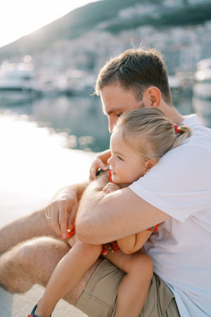 Dad hugs a little girl sitting on his lapの写真素材