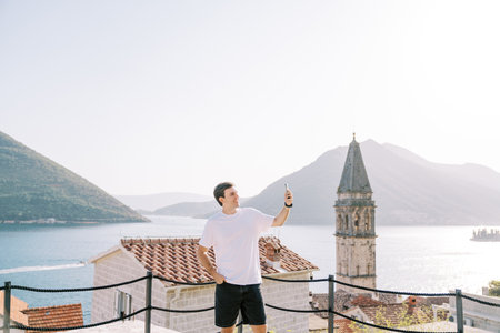 Smiling guy takes a selfie while standing on a platform overlooking the Bay of Kotor. Perast, Montenegroの写真素材