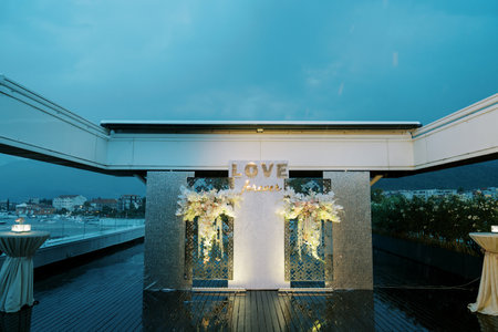 Illuminated stand with bouquets of flowers on the terrace near the tables.の写真素材