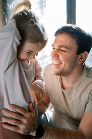 Smiling dad holds the waist of a little girlの写真素材