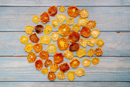 Fruit chips are laid out in a circle on blue worn horizontal wooden planksの写真素材