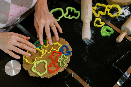 Confectioner distributes multi-colored cookie cutters over the dough on the table. Croppedの写真素材