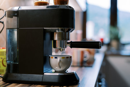 Coffee dripping from the portafilter of a carob coffee machine into a cup on a standの写真素材