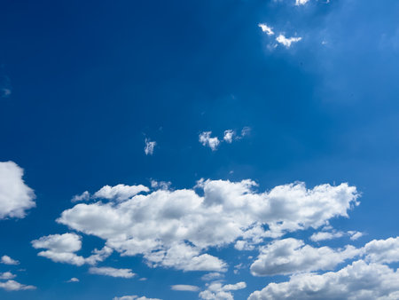 White cumulus clouds in the blue sky in the bright rays of the sunの写真素材