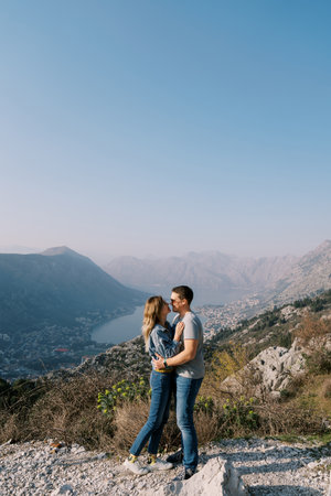 Man and woman embrace and almost kiss on a mountain overlooking the Bay of Kotor. Montenegroの写真素材