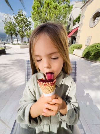 Little girl licks popsicles in a coneの写真素材