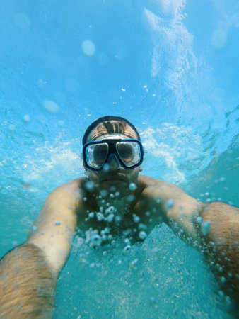 Swimmer in goggles dives under the water, raising splashesの写真素材
