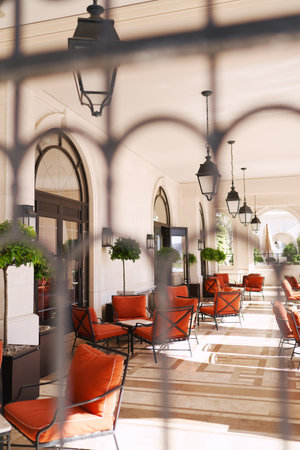 View through the wrought-iron lattice onto the hotel terrace with soft chairs and tablesの写真素材